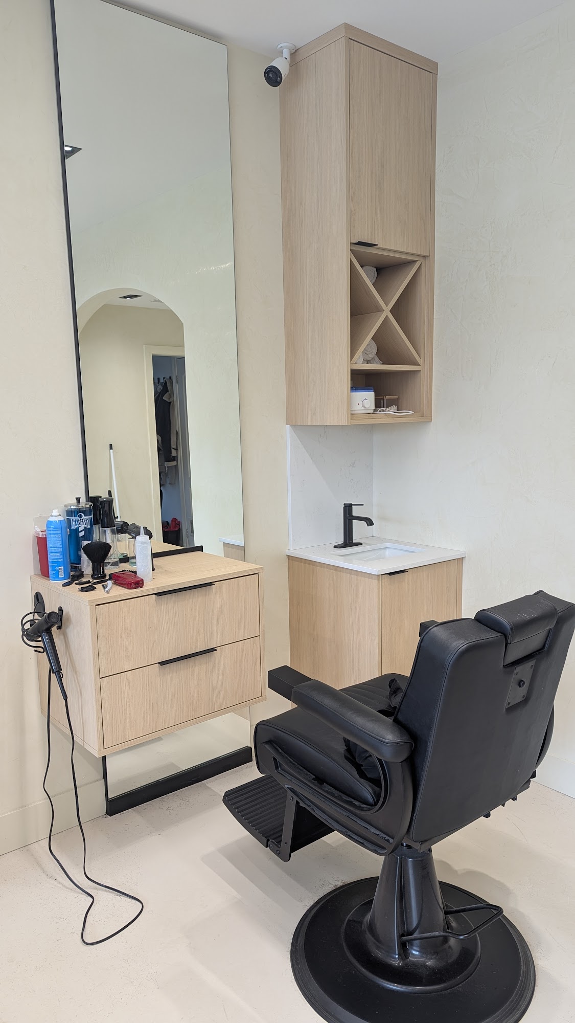 Barber station at Supreme Cuts: black chair, oak cabinet, black hardware